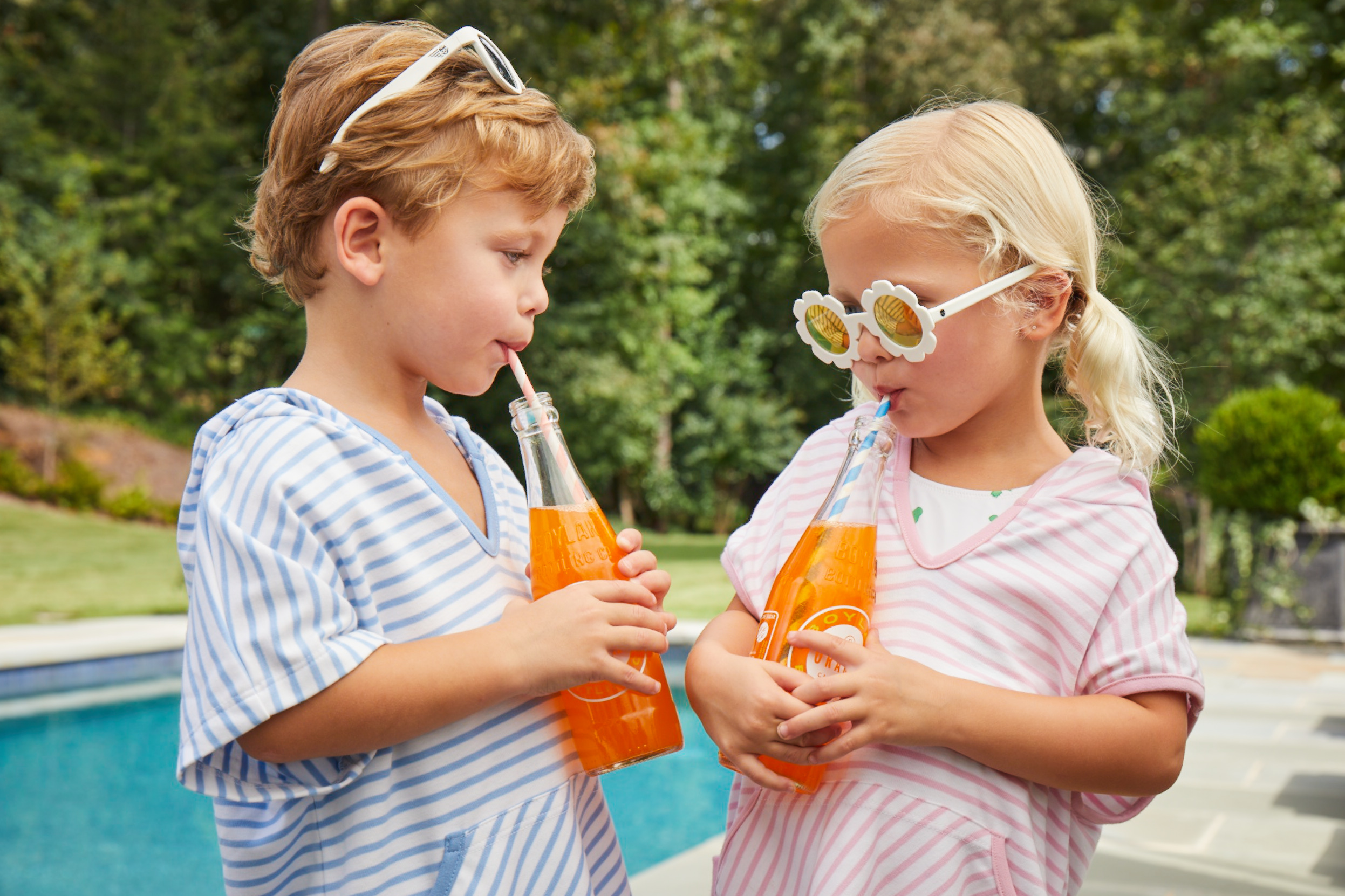 Boy and girl drinking sodas by the pool