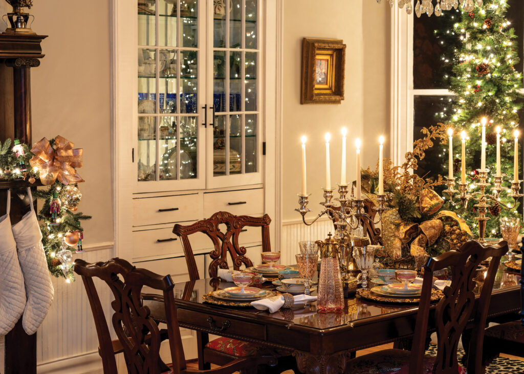 Table set for a Christmas dinner with lit Christmas tree in the background