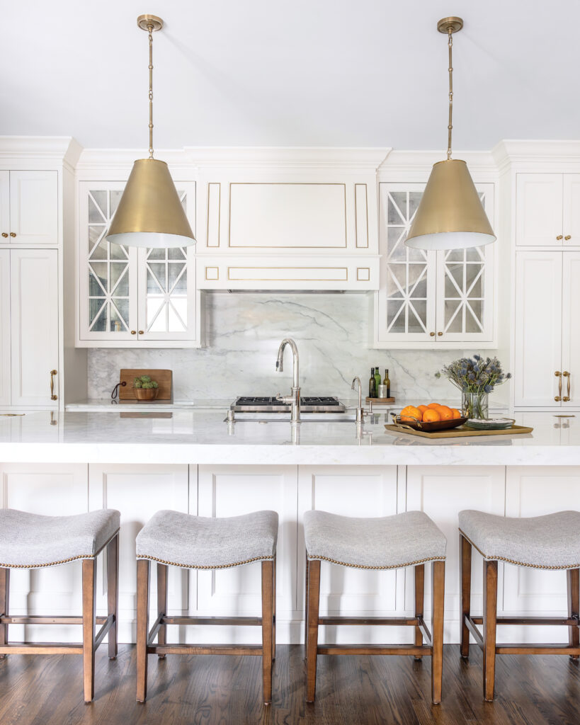 White kitchen island with gold light fixtures 