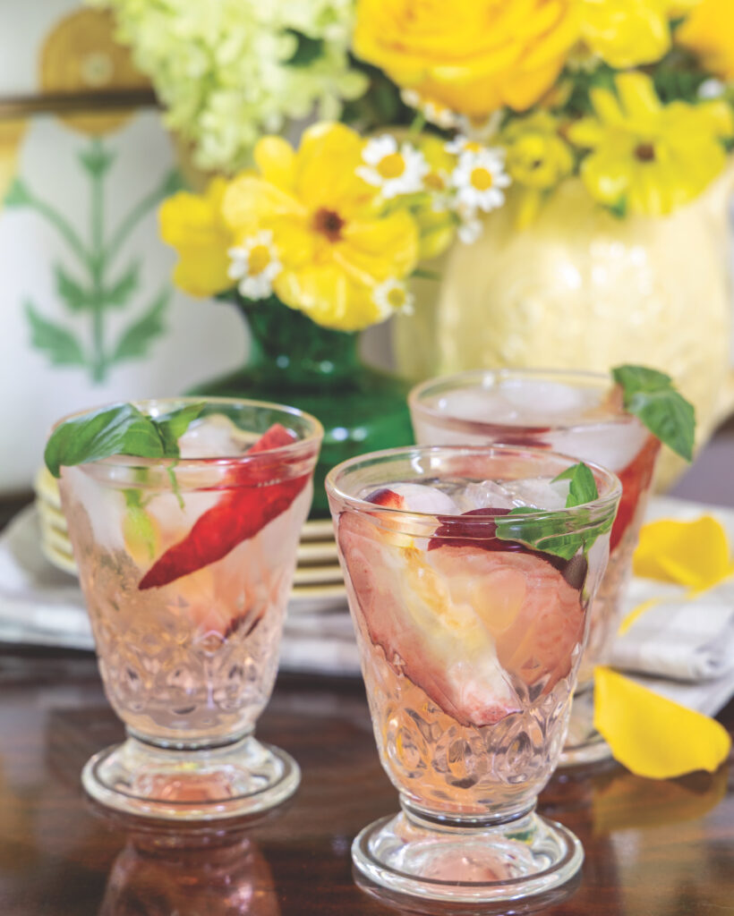 Three glasses of White Peach Sangria with yellow flowers behind.