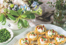 4 Garden-Fresh Recipes for a Lively Spring Menu Herb and goat cheese tartlets lined up on a platter surrounded by herbs and flowers.