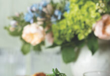 Crab Cakes with Parsley Caper Sauce Three crab cakes stacked together with limes on the side, and a green sauce in the background.