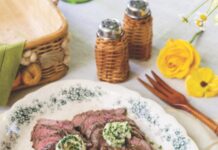 Garlic Butter Steak Slices of steak on a blue and white platter topped with garlic herb butter.