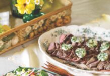 Panzanella Salad Panzanella salad in an oval serving dish with a platter of steak in the background.