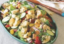 Panzanella Salad Panzanella salad in an oval serving dish with a platter of steak in the background.