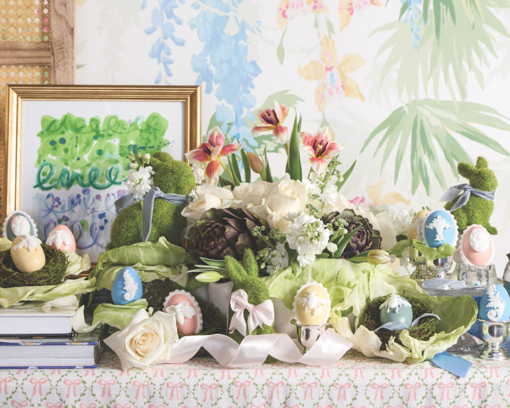 A colorful display of pink, blue, and yellow Wedgwood-inspired eggs with books, paintings, and ribbons around them.