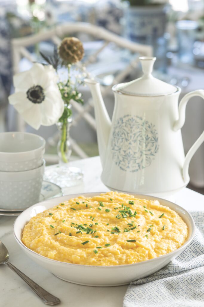 Double Cheese Grits served in a white bowl topped with chives.
