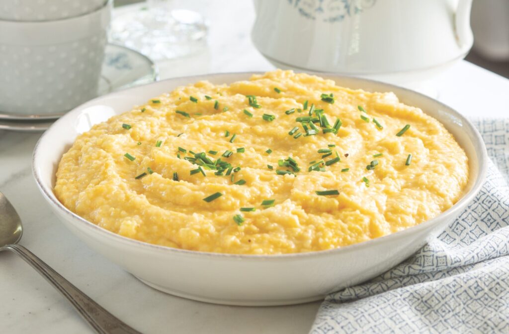 Double Cheese Grits served in a white bowl topped with chives.