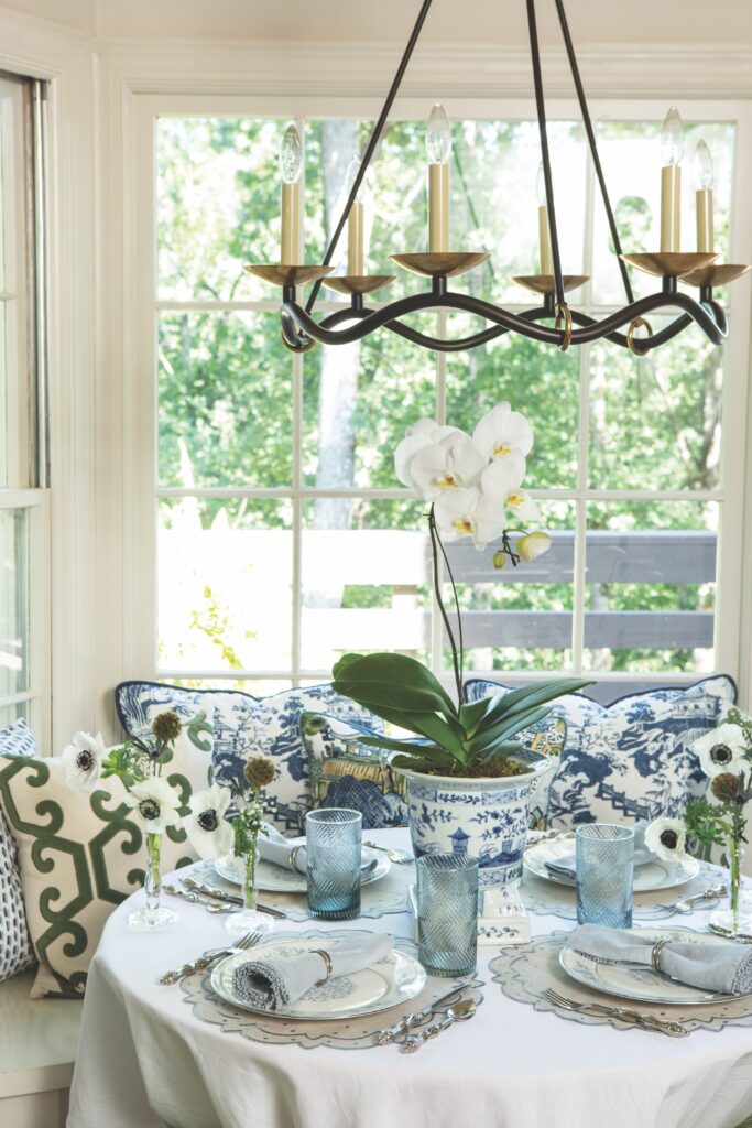 A breakfast nook set with blue and white tableware with a white orchid as a centerpiece.