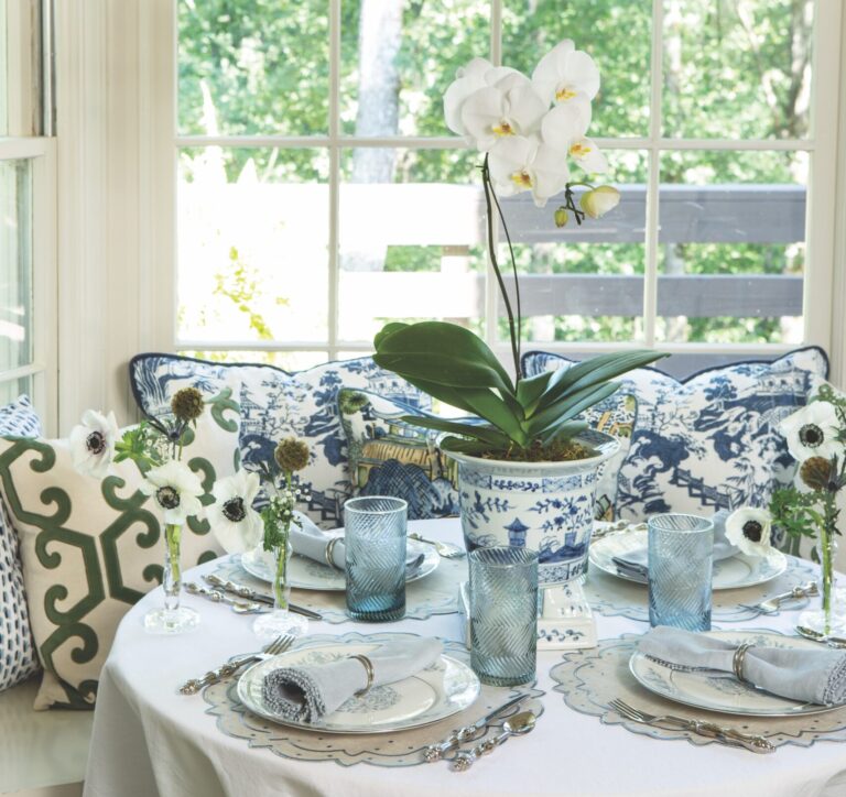 A breakfast nook set with blue and white tableware with a white orchid as a centerpiece.