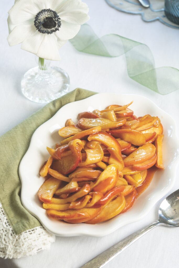 Cinnamon Apples on a white platter, with a white anemone flower behind it