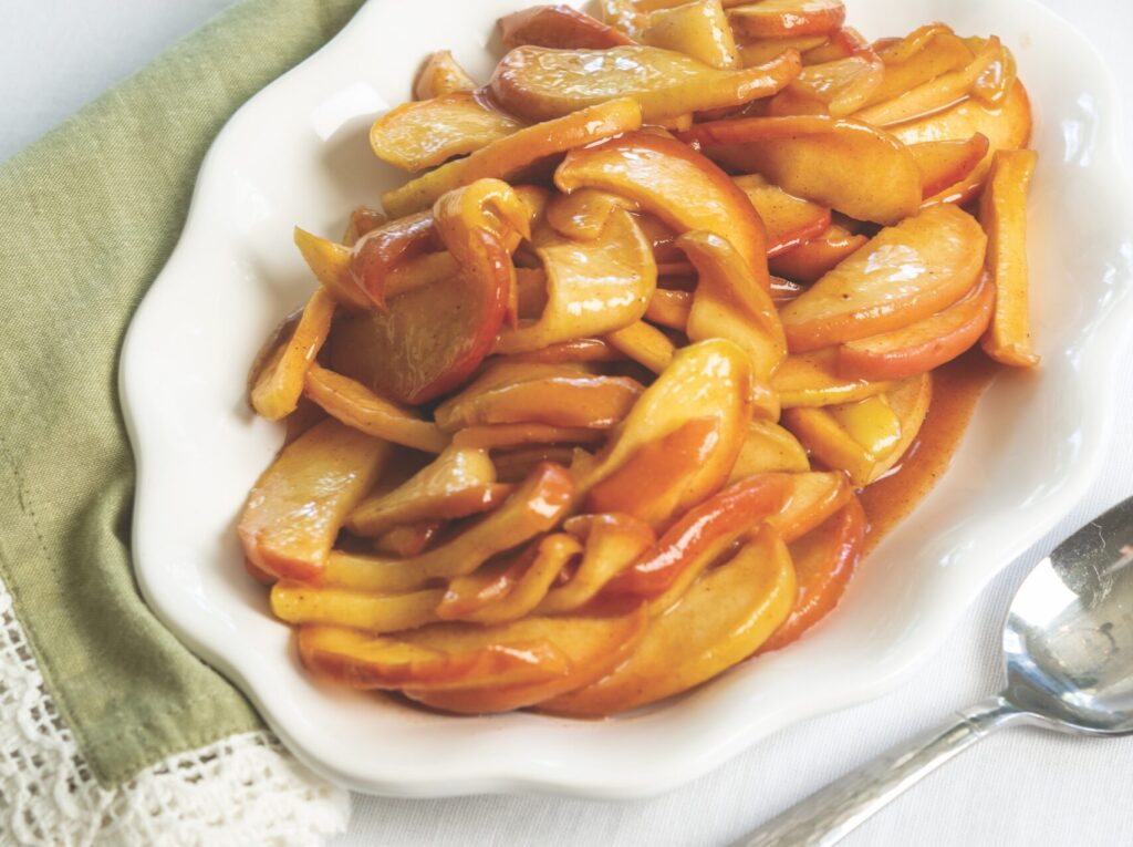 Cinnamon Apples on a white platter, with a white anemone flower behind it