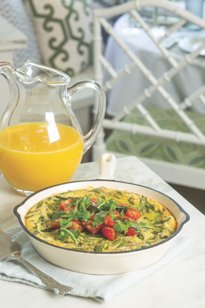 Arugula and Tomato Frittata in a cast iron skillet, with a pitcher of orange juice.