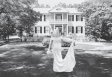 An Alabama Wedding Offers Harmonious Beginnings A black-and-white photo of a bride standing in front of a white manor.