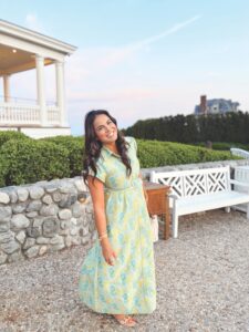Alexa Archibald standing in front of a stone wall and white bench.