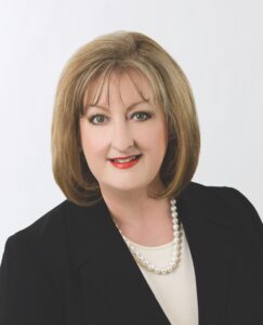 Portrait of Phyllis Hoffman DePiano in a black suit and pearl neckalce.