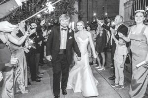 A bride and groom walk through a tunnel of sparklers as they exit their wedding.