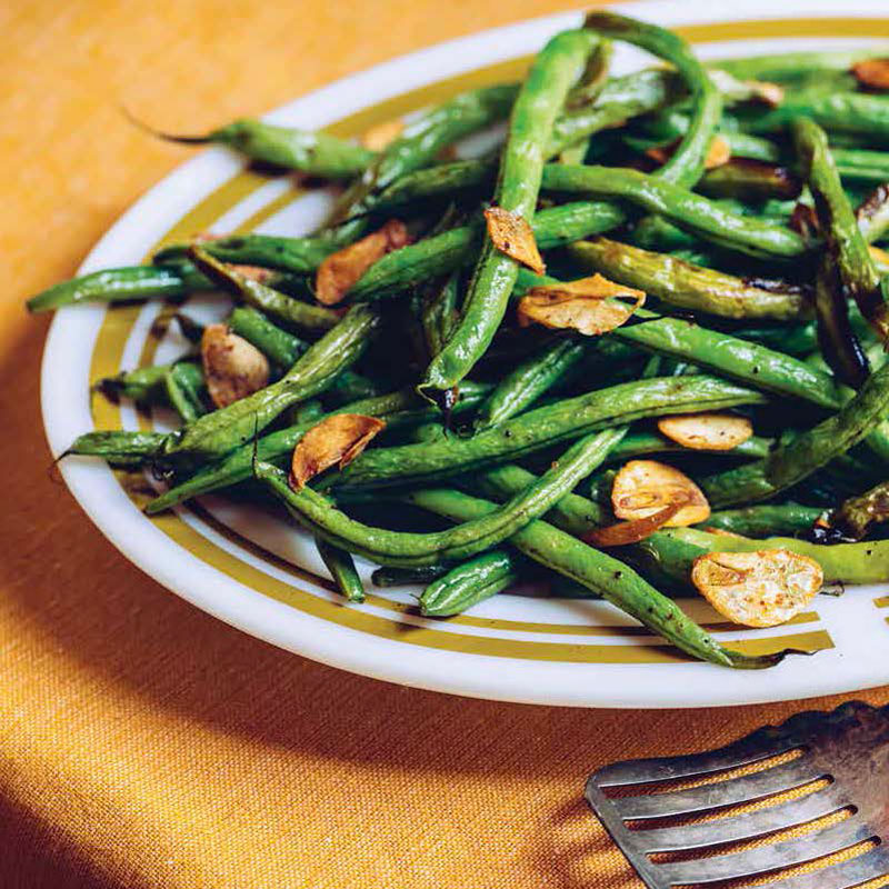 Green beans sautéed with garlic on a white and gold-rimmed plate. (side dish)