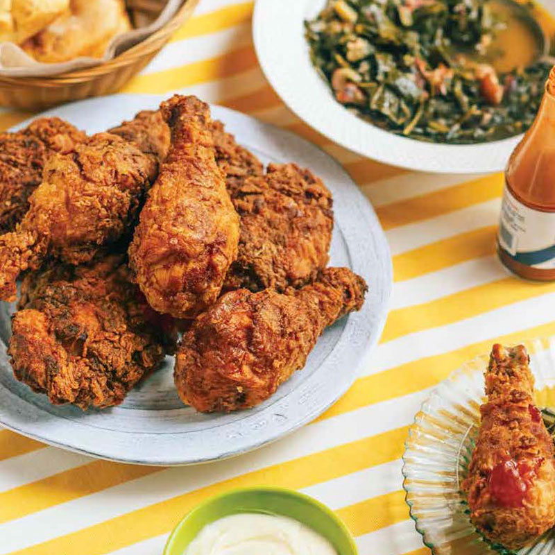 Plate of crispy fried chicken pieces on a blue plate, with dips and a yellow-striped tablecloth in the background.